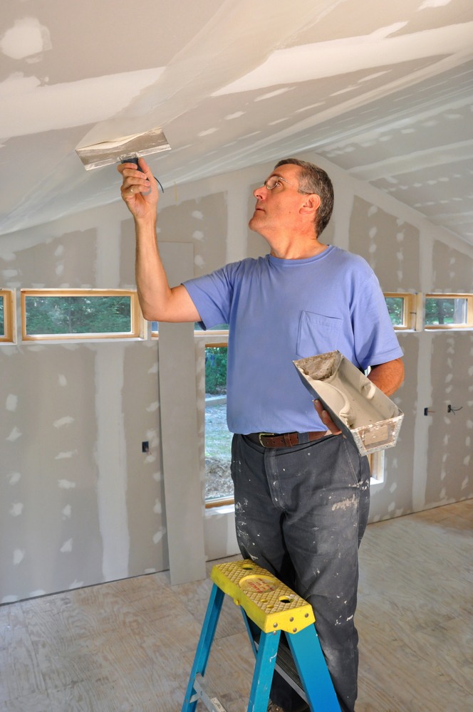 man applying joint compound on drywall ceiling